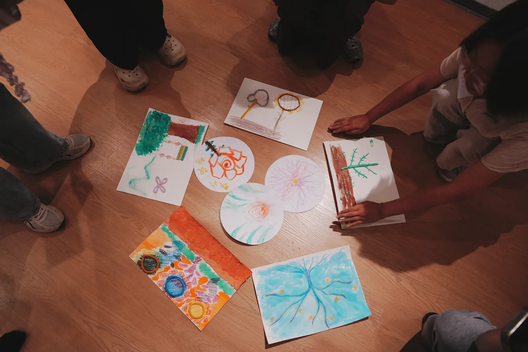 A group reflecting together on artworks arranged across the studio floor